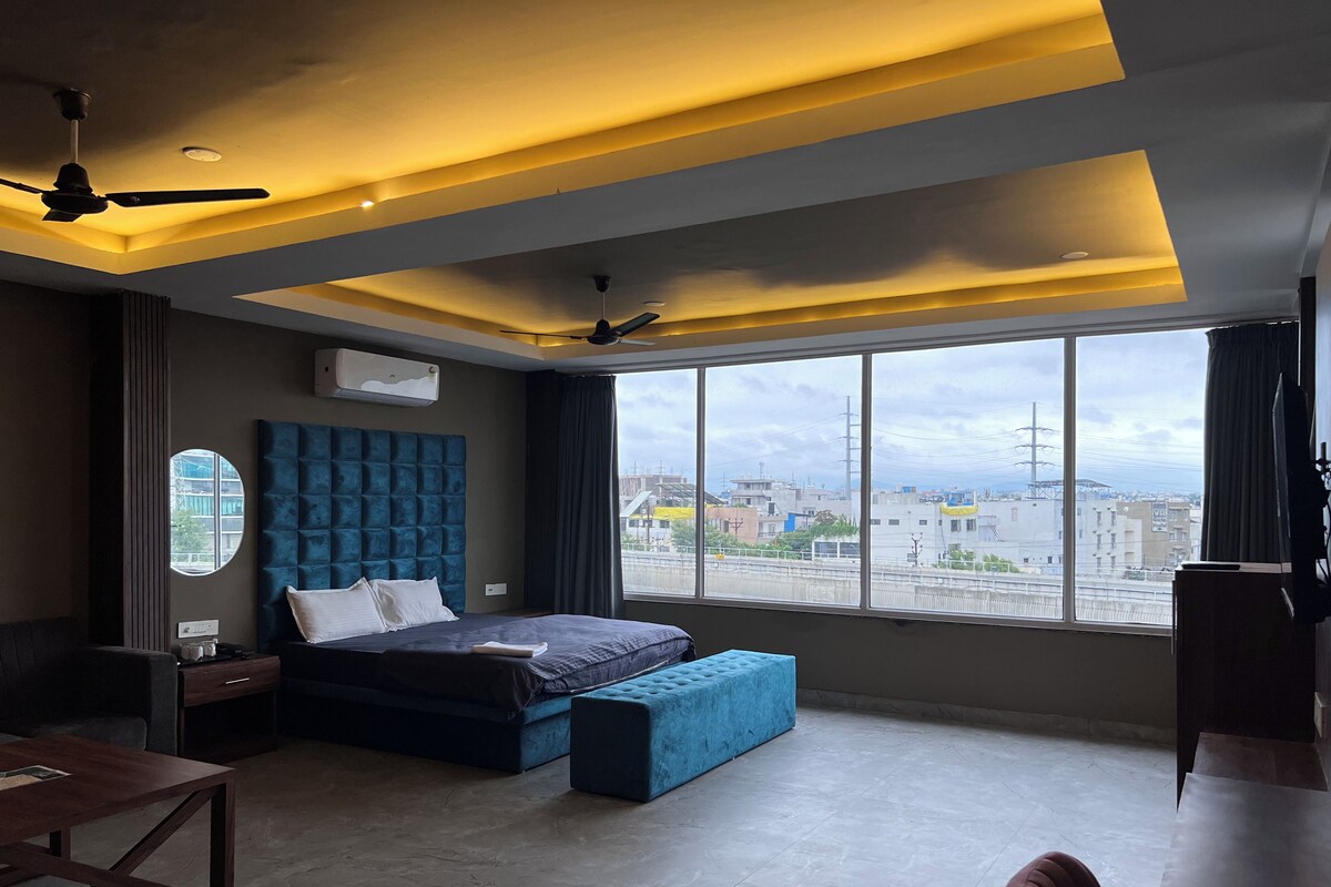 Un dormitorio moderno con una cama grande, un escritorio y vistas de la ciudad.