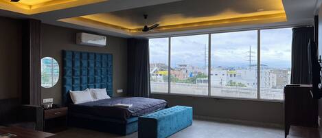 A modern bedroom with a large bed, a desk, and a view of the city.