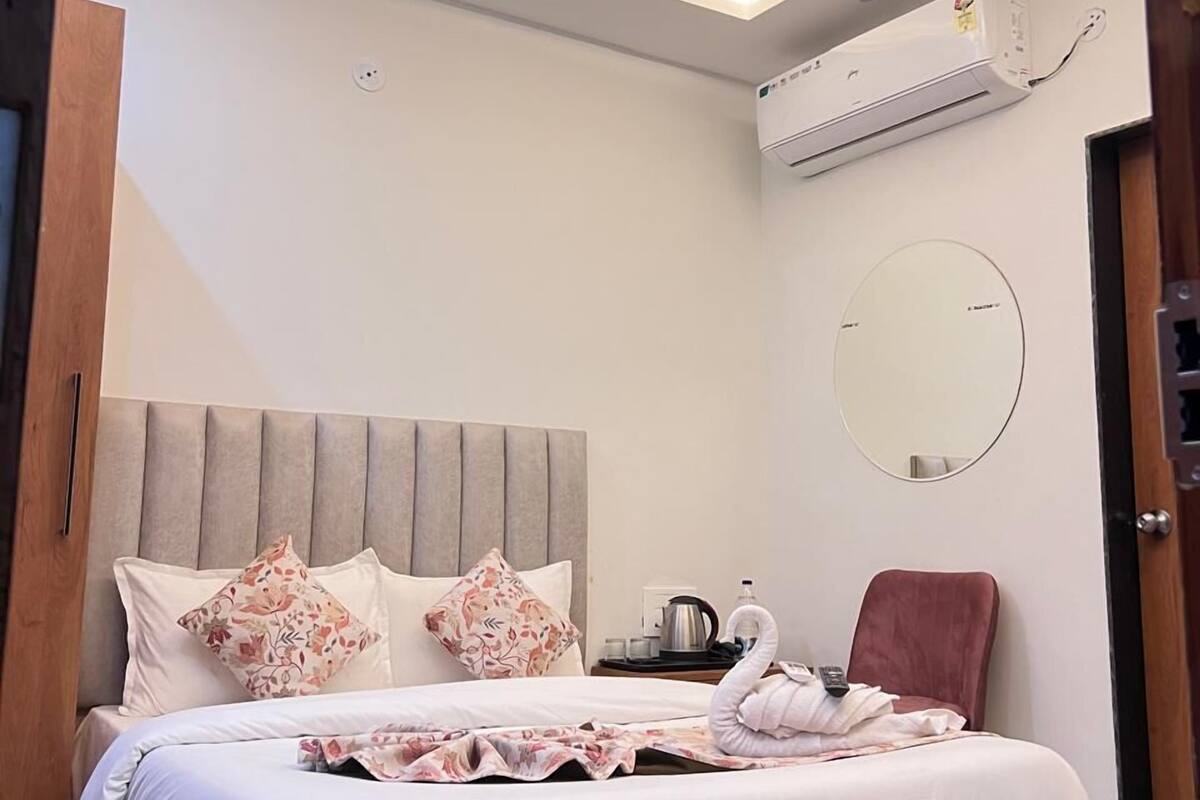 Ein modernes Schlafzimmer mit einem Bett, einem Deckenventilator, einer Klimaanlage, einem runden Spiegel und einem roten Sessel.