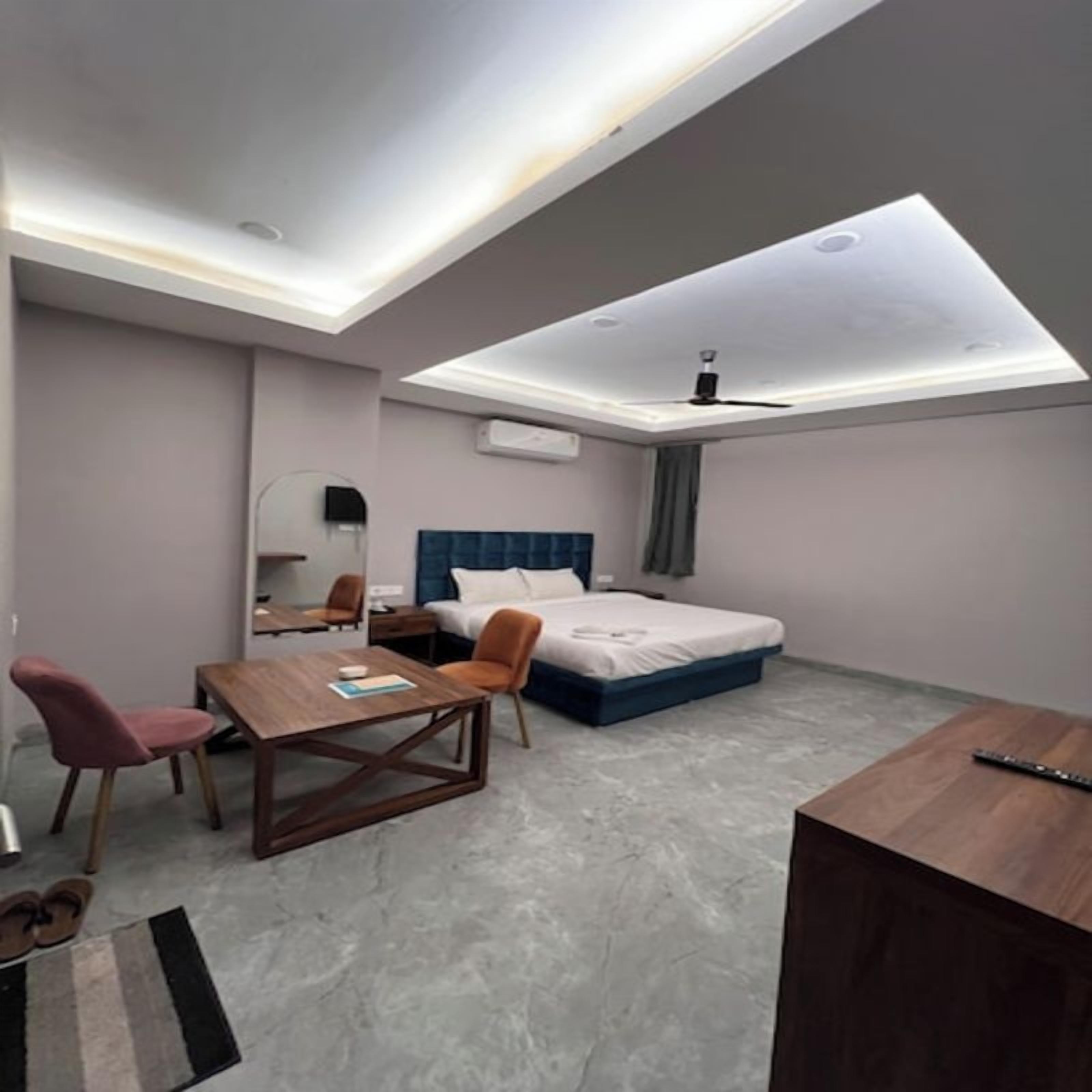 Una habitación de hotel moderna con una cama, un escritorio, una silla y una mesita.