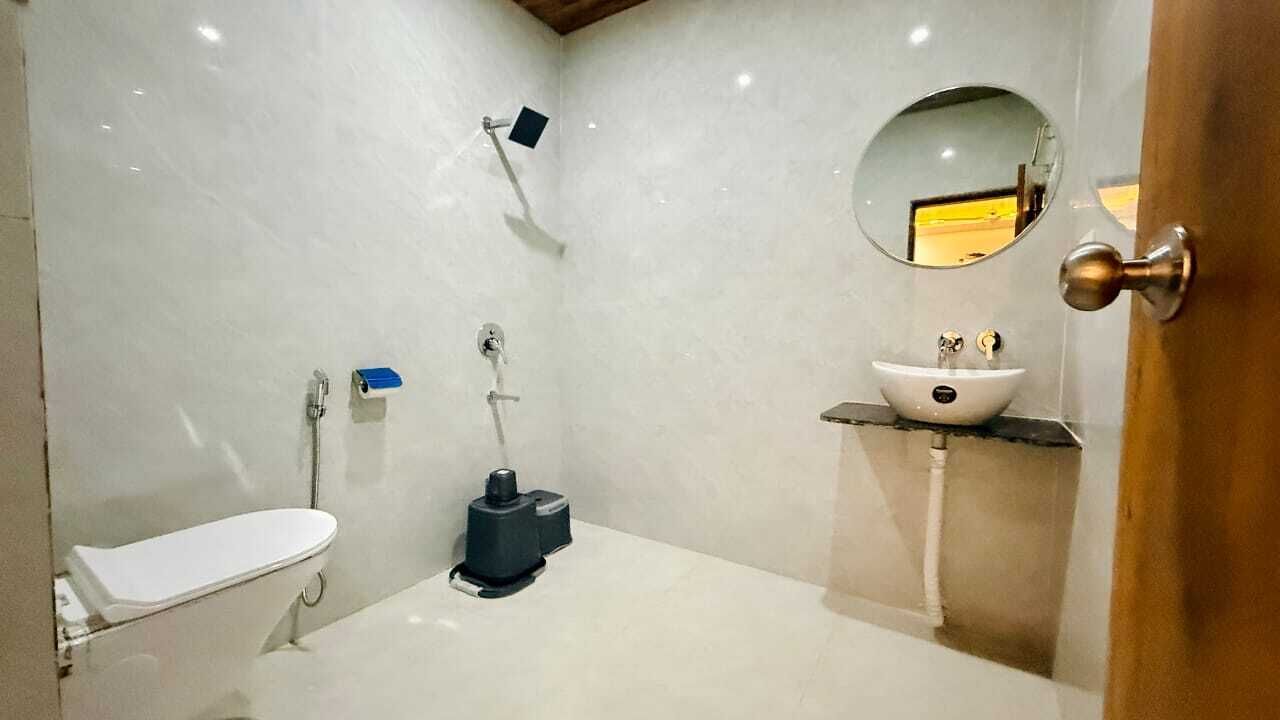 A bathroom with a toilet, a sink, a shower, and a mirror.