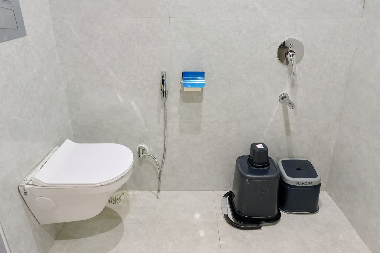 A modern bathroom with a toilet, bidet, and two black trash bins.
