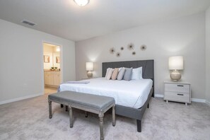 A bedroom with a bed, bedside tables, a bench, and a door leading to a bathroom. - Family-Friendly 5BR Windsor Island Retreat with Pool (Davenport)