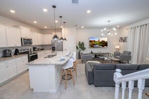 A modern kitchen with white cabinets, a granite countertop, and a central island with bar stools. - Exclusive Villa, Full Resort Access! (Davenport)