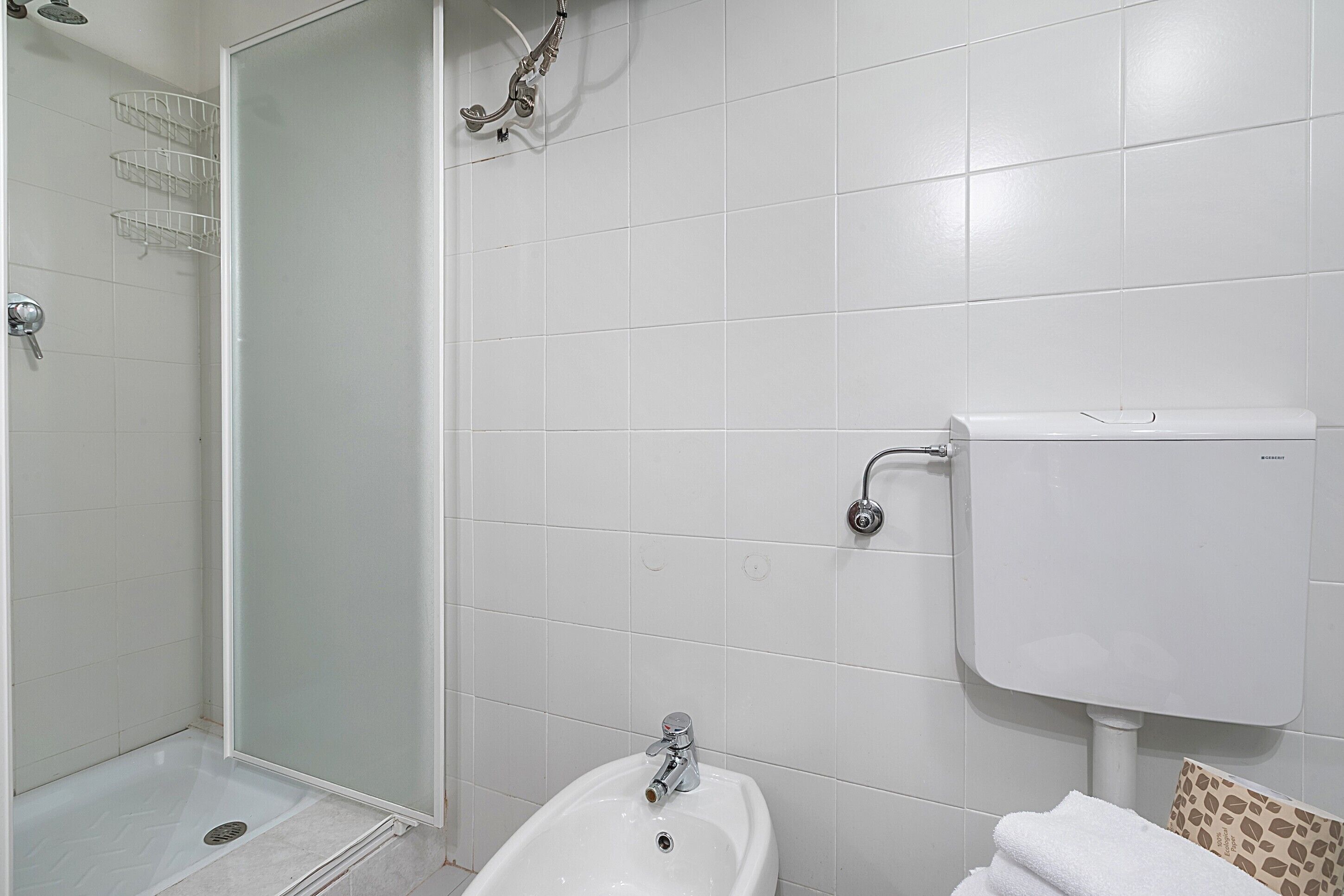 A bathroom with a shower, toilet, sink, and towel rack.