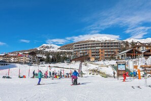Een skigebied met meerdere gebouwen, skiliften en een berg bedekt met sneeuw.