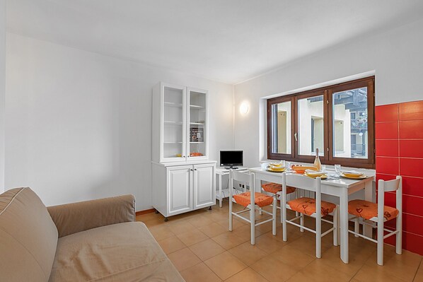 A compact living space with a sofa, dining table, chairs, a white cabinet, and a window with a view. - La Piazzetta - Flat With Parking for 4 (Sauze di Cesana)