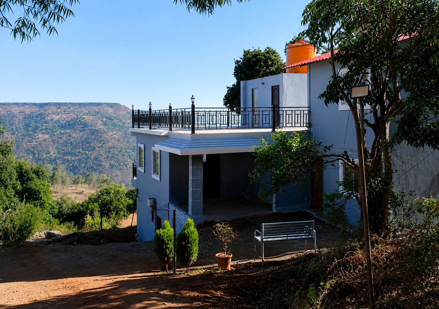 Ein zweistöckiges Haus mit Balkon, einem kleinen Garten und Blick auf die Hügel.