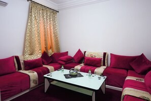 A living room with two red sofas, a white coffee table, and patterned curtains. - ABOUAB GUELIZ 2 APARTMENT MARRAKECH (Marrakech)