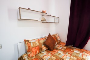A bed with a patterned bedspread, a brown pillow, and two wall-mounted shelves with decorative items. - ABOUAB GUELIZ 2 APARTMENT MARRAKECH (Marrakech)