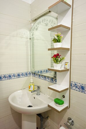 A bathroom with a white sink, a mirror, and shelves with toiletries. - ABOUAB GUELIZ 2 APARTMENT MARRAKECH (Marrakech)