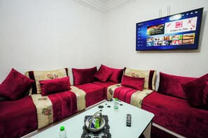 Ein modernes Wohnzimmer mit einem Ecksofa, einem Couchtisch und einem an der Wand montierten Flachbildfernseher, der eine Speisekarte zeigt.