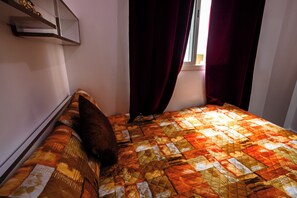 Ein Bett mit Bettdecke, Kissen und einem Fenster mit Vorhängen.