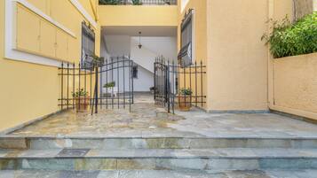 Eine Steintreppe führt zu einem Balkon mit Topfpflanzen und einem Metallgitter.
