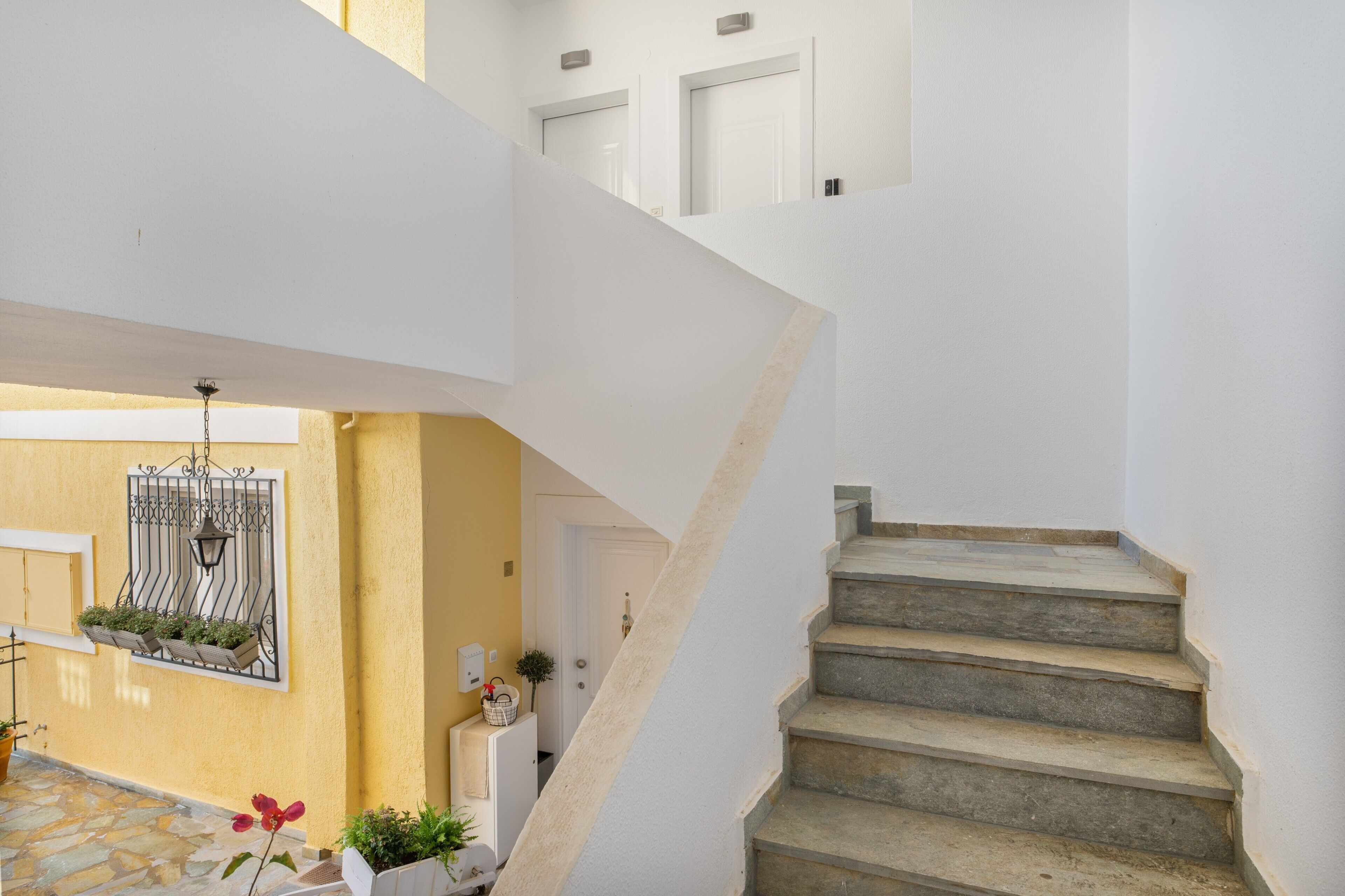 A staircase leading to a second floor, a yellow wall with a window, and a door.