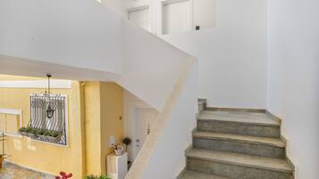 A staircase leading to a second floor, a yellow wall with a window, and a door.