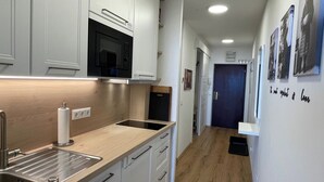 Una cocina moderna con gabinetes blancos, un microondas negro y una encimera de madera.