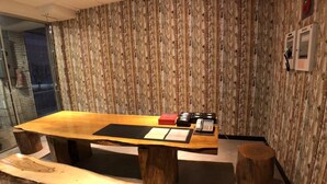 A wooden reception desk with a bench, a telephone, and a small red box. - 128 INN- Self Check In (Taipei)