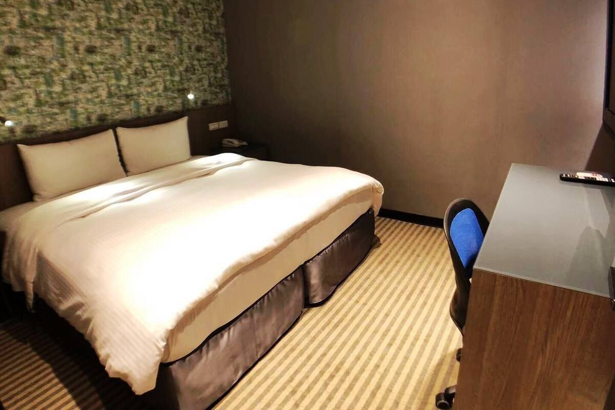 A hotel room with a large bed, a desk, and a telephone.