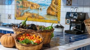 Un plan de travail de cuisine avec deux paniers en osier remplis de légumes et une citrouille.