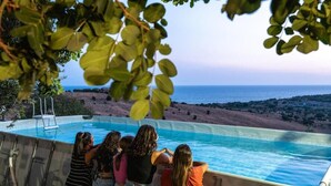 Un groupe de personnes se tient près d’une piscine, avec vue sur la mer.