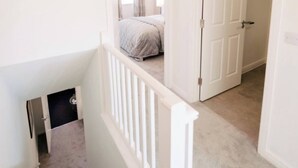 Un dormitorio con una cama, una puerta y una escalera.