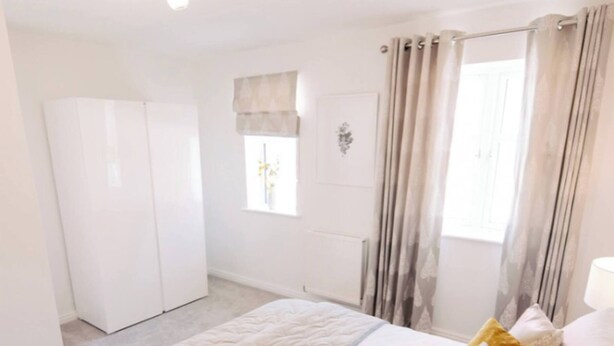 Un dormitorio con una cama, cortinas, una ventana y una lámpara en el techo.