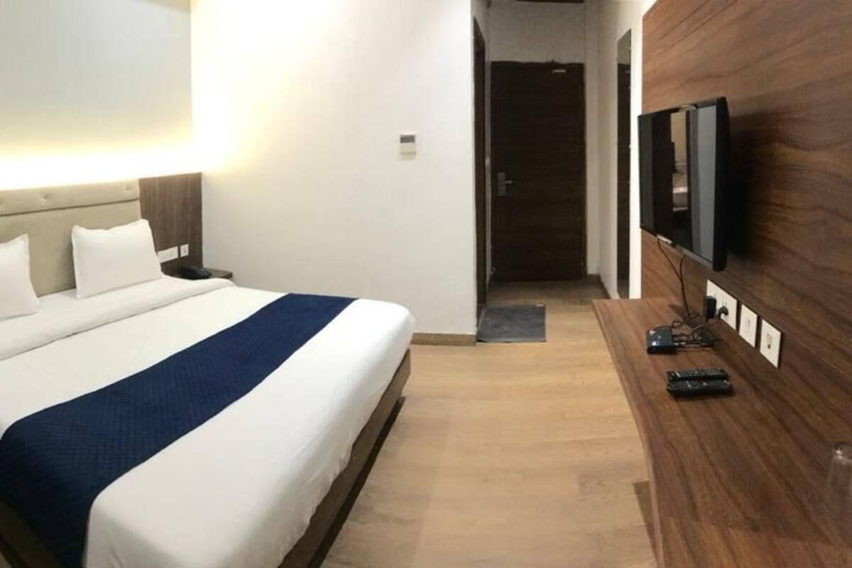 Une chambre d’hôtel avec un lit, une table de chevet, une télévision et une chaise.