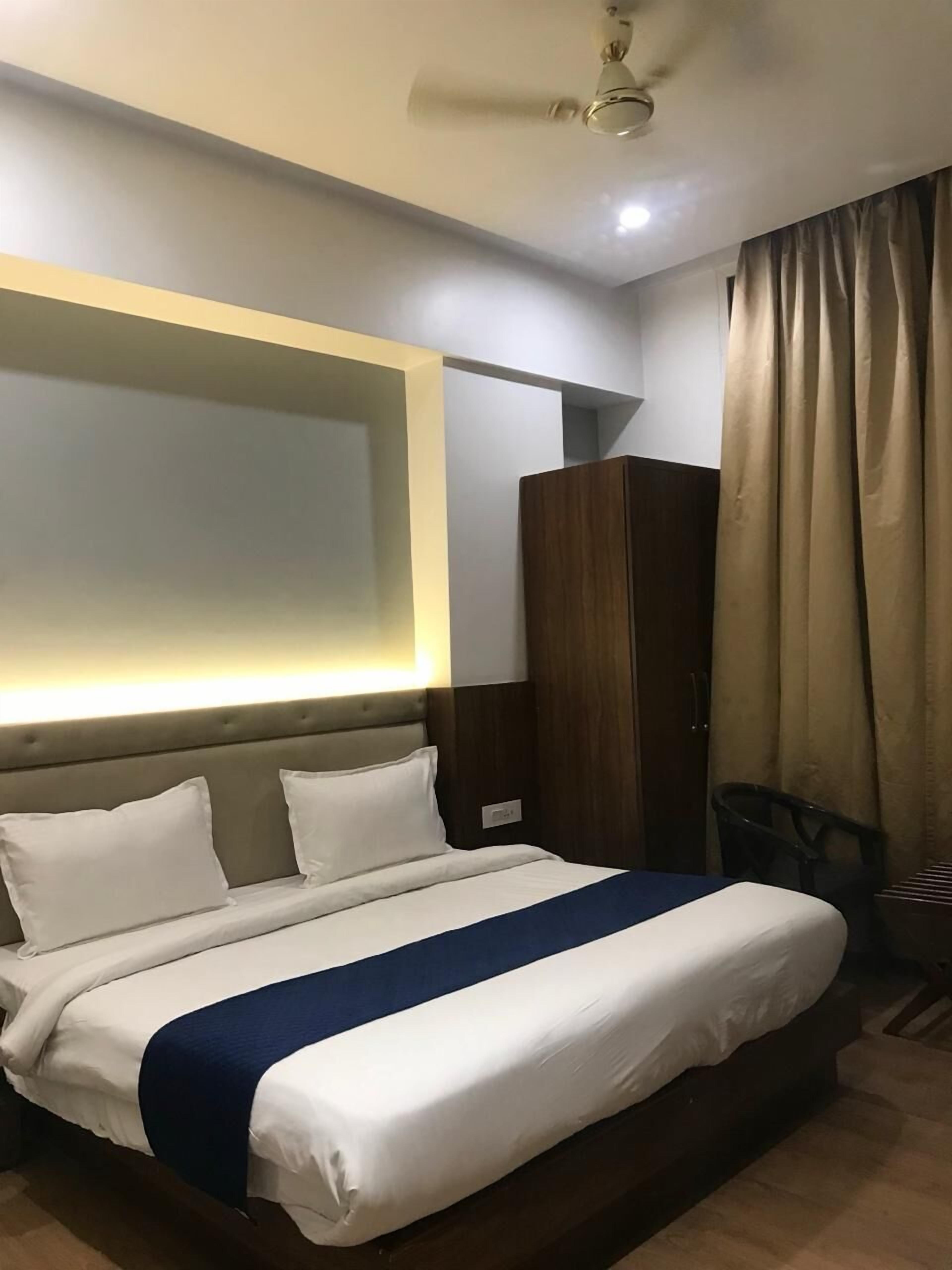 A hotel room with a bed, a wardrobe, a ceiling fan, and a curtain.