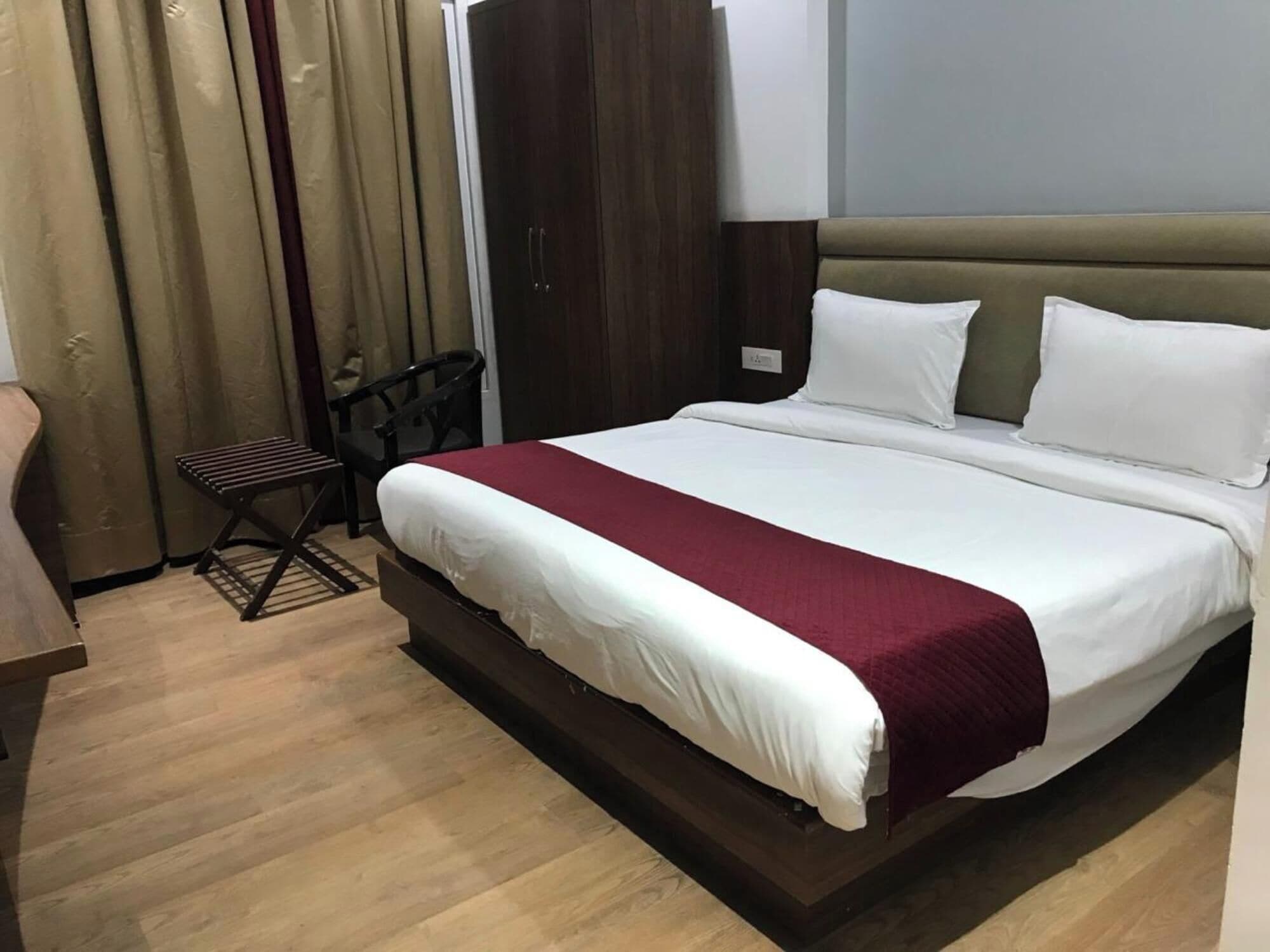 Une chambre d’hôtel avec un grand lit, une table de chevet en bois, une petite table et une chaise.