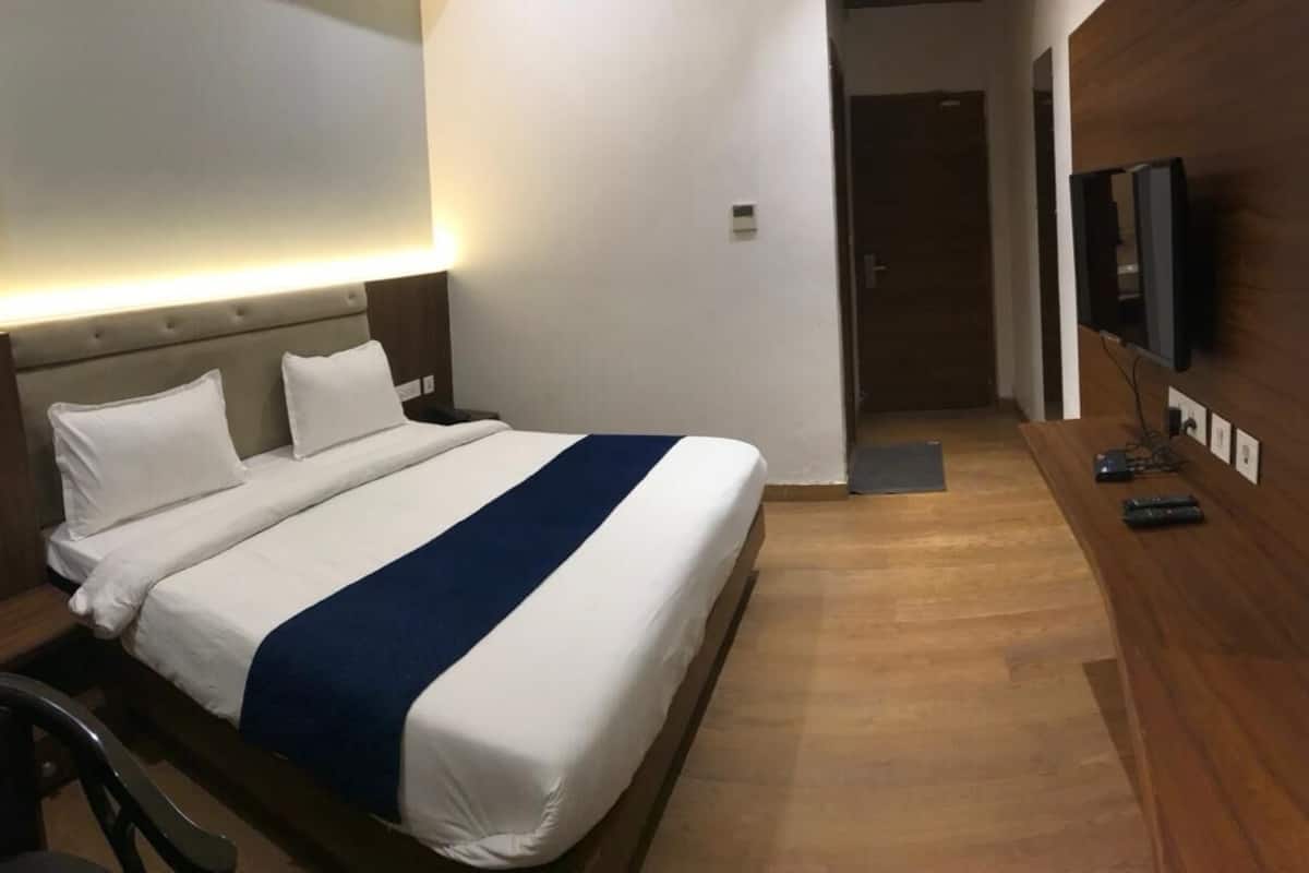 Une chambre d’hôtel avec un lit, une table de chevet, une télévision et un plancher en bois.