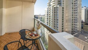 Een balkon met een gedekte tafel, met uitzicht op een stadsgezicht met wolkenkrabbers.