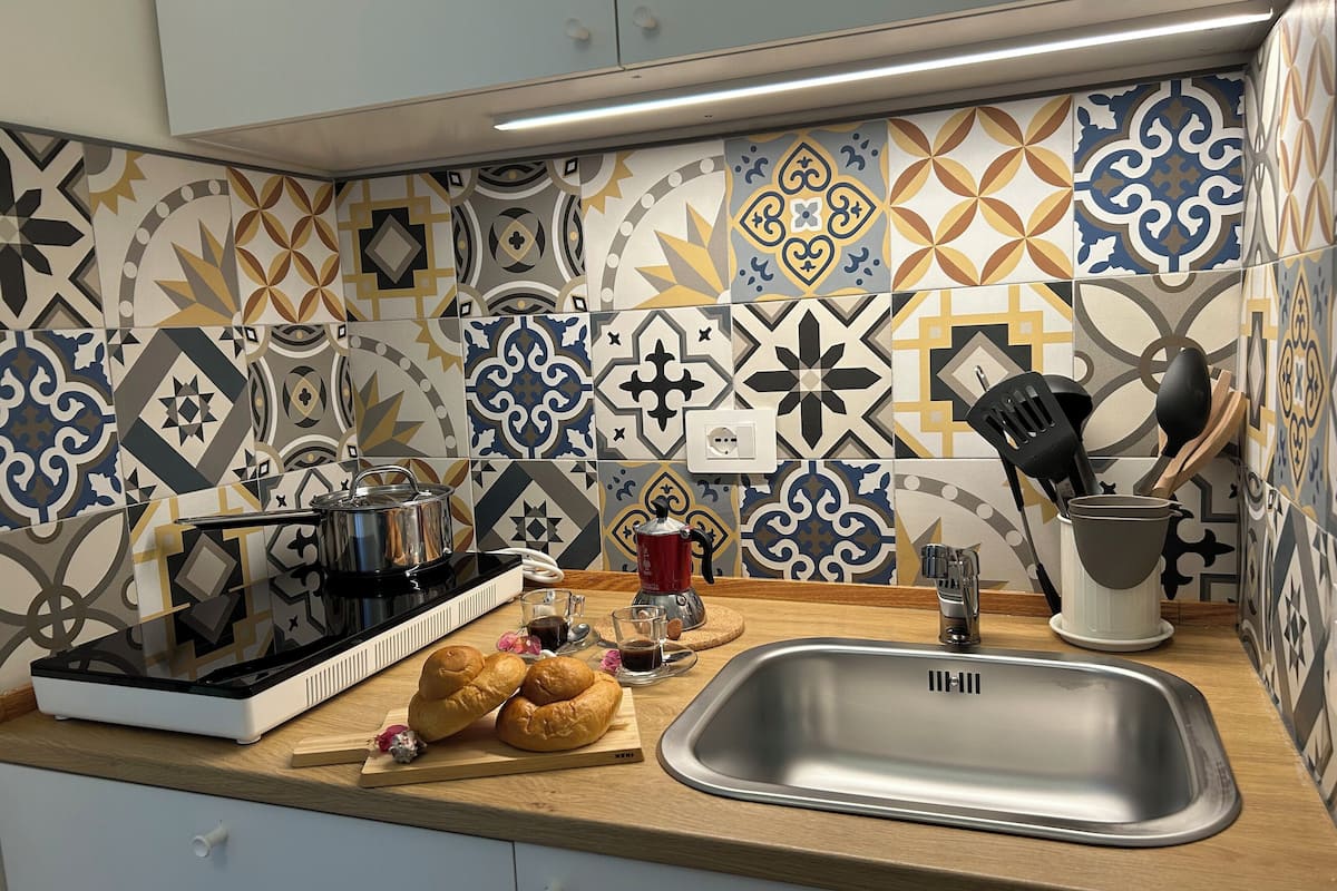 Une cuisine avec des carreaux décoratifs, un évier en acier inoxydable, une machine à café et un grille-pain.