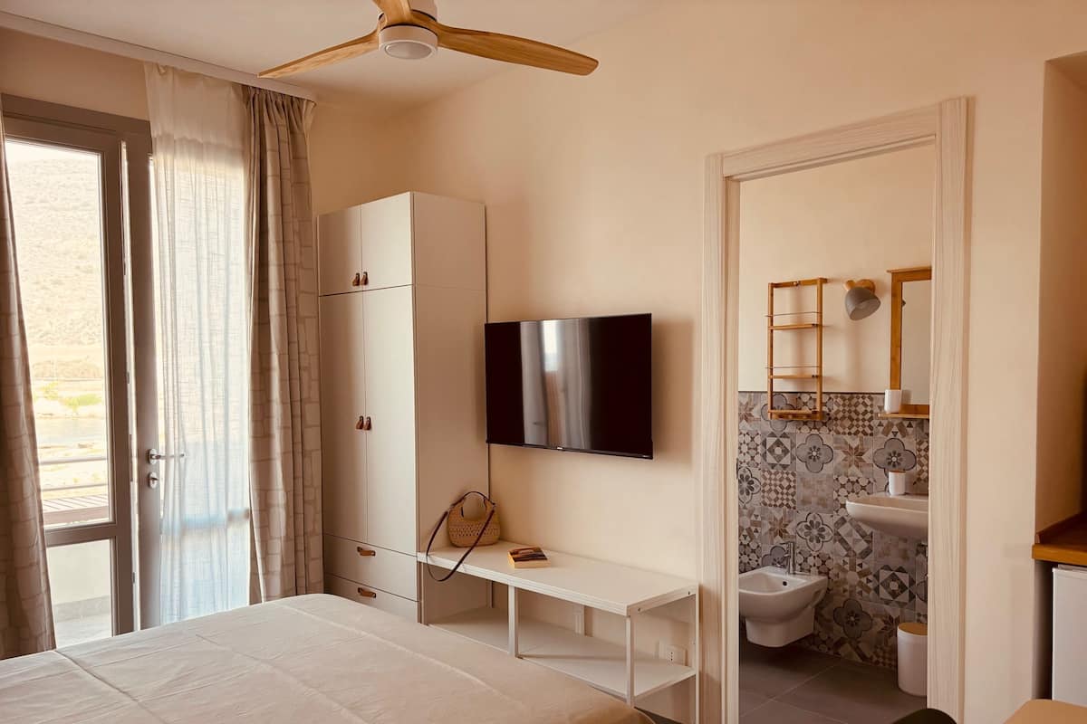 Une chambre à coucher comprenant un lit, une armoire, une télévision, un bureau et une salle de bain avec des toilettes et un lavabo.