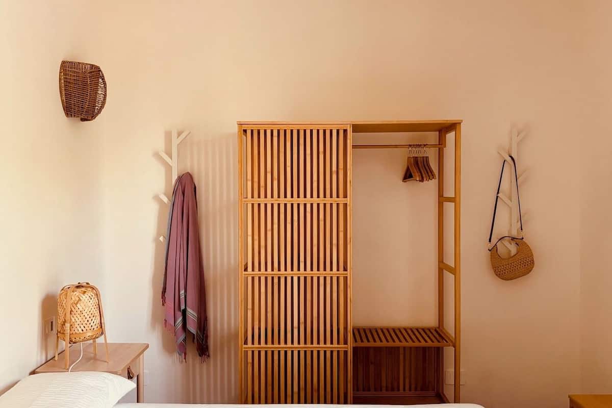 Une chambre à coucher avec un lit, une armoire en bois, un panier suspendu et une étagère.