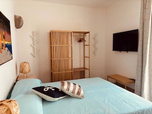 A bedroom with a bed, a TV, a wooden shelf unit, and a painting on the wall. - One-Bedroom Apartment with Sea View and Terrace (Trapani)
