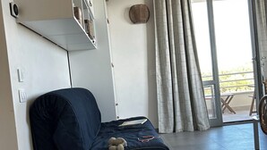 Una stanza con un letto, una ventola a soffitto, una finestra con tende e vista all'esterno.