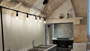 Una cocina moderna con pared de piedra, una isla integrada con fregadero y un refrigerador pequeño.