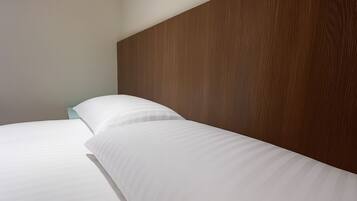 A neatly made bed with white linens and a wooden headboard in a hotel room.