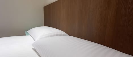 A neatly made bed with white linens and a wooden headboard in a hotel room.