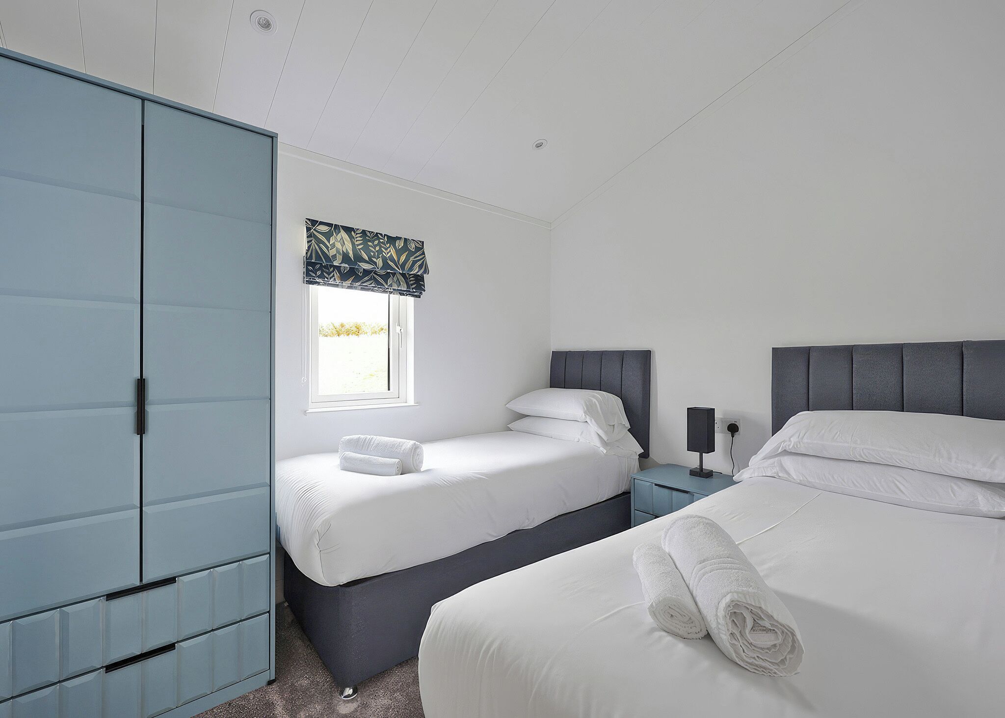 Een slaapkamer met een bed, een kledingkast, een nachtkastje en een raam met uitzicht.