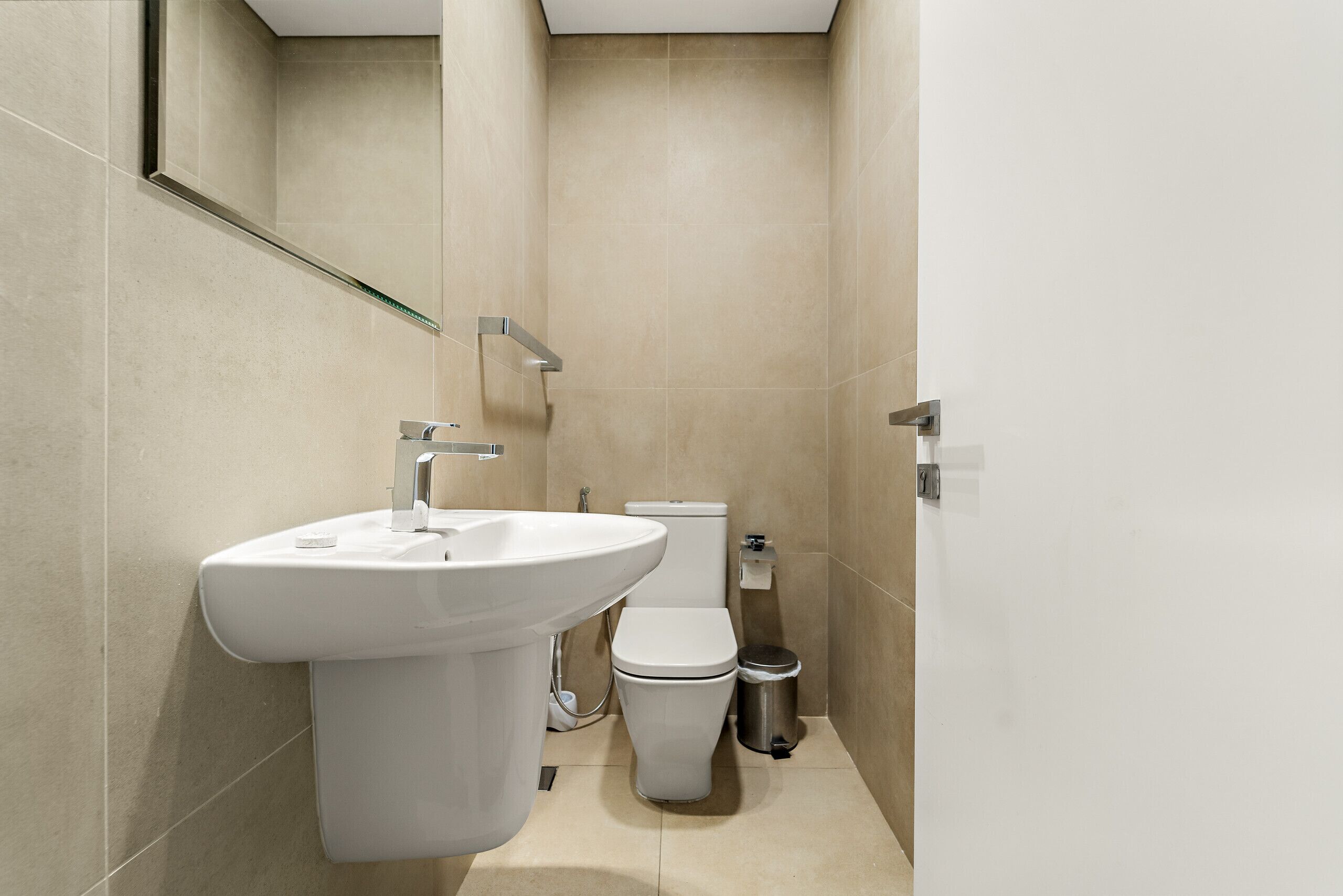 Un baño moderno con lavamanos pedestal, inodoro y cubo de basura.