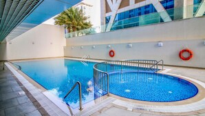 An indoor swimming pool with clear water, surrounded by a tiled floor and a glass wall. - Stylish 2BR in Dubai Marina Near the Beach (Dubai)