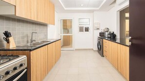 A modern kitchen with wooden cabinets, a gas stove, a sink, and a washing machine. - Elegant Waterfront Villa W Sunset Terrace (Ajmal Makan)