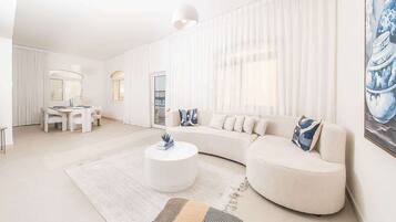 Een moderne woonkamer met een witte bank, een ronde salontafel en een kamerkleed met een patroon.