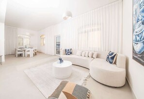 Ein modernes Wohnzimmer mit einem weißen Sofa, einem runden Couchtisch und einem gemusterten Teppich.