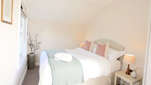 Un dormitorio ordenado con una cama, mesitas de noche y un ventanal.