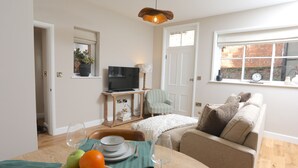 Una sala de estar acogedora con una mesa de comedor para dos personas, un televisor y un sofá cómodo.