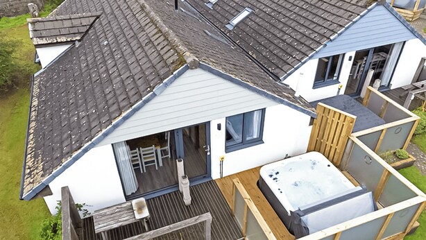A residential property with a sloped roof, a hot tub, and a deck. - Ocean Tide Villa 3 Hot Tub (Woolacombe)