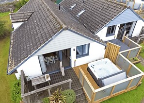 A residential property with a sloped roof, a hot tub, and a deck. - Ocean Tide Villa 3 Hot Tub (Woolacombe)
